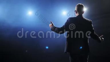 在黑暗的会议厅里通过麦克风讲话的人的后视图。 在<strong>记者招待会</strong>上，男人谈论麦克风